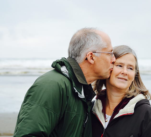 elderly couple kissing on a beach