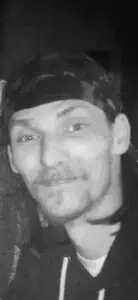 Black and white image of a person in a bandana and hoodie, smiling subtly at the camera; Alabama funeral home offering compassionate cremations, funerals, pre-planning services.