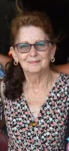 Elderly woman with glasses in a floral top, standing outside, representing cremation and funeral services offered by Alabama funeral homes.