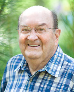 An older man in glasses smiles outdoors, representing Alabama funeral home services.