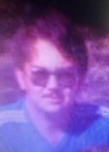 Blurry person in sunglasses at Alabama funeral home, neutral expression.