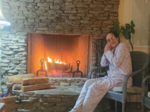 A woman reflects by a fireplace, considering cremation and funeral services in Alabama.