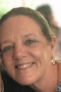 A woman with light skin and blue eyes, smiling at a funeral home in Alabama.