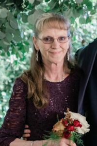 Older woman in a purple dress holds flowers for a funeral at Alabama funeral home.