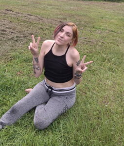 A person sits on grass making peace signs, symbolizing remembrance at an Alabama funeral home.