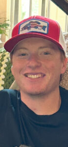 Smiling person in funeral home, Alabama, with plant; cremation services and burial info.